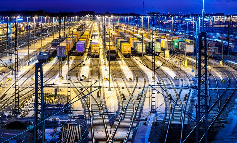 Freight train cars stationed on multiple rows at an industrial docking station by night.