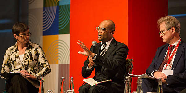 Kate Sturgess, moderator, Herman Warren and William Gains discussing around a table.
