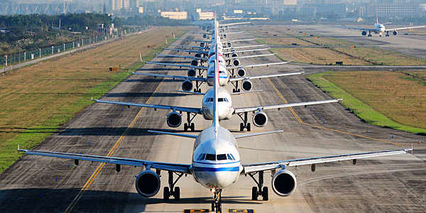 Airplanes line up on runway for departure.