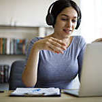 Close-up of young woman with headphones engaged in a video conference from home.
