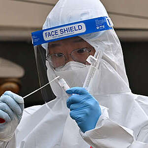 A medical staff member wearing protective gear takes a swab from a visitor to test for the Covid-19 coronavirus at a temporary testing station outside the City Hall in Seoul on December 28, 2020. (Photo by Jung Yeon-je / AFP) (Photo by JUNG YEON-JE/AFP via Getty Images)