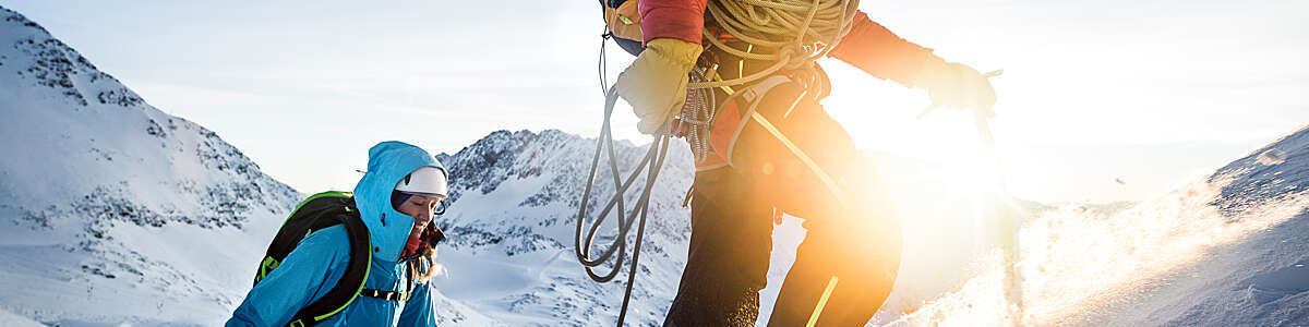 Mountain climbers leading up a snowy ridge at sunrise.