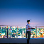 Businessman using a laptop on the rooftop of a skyscraper